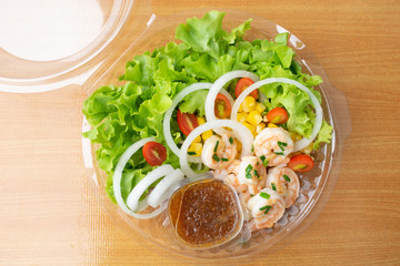 Shrimp salad with corn,green oak, onion and tomato in clean plastic box.