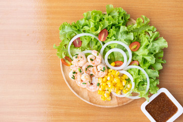 Shrimp salad with corn,green oak, onion and tomato in wooden dish.