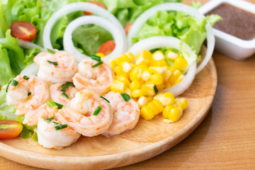 Shrimp salad with corn,green oak, onion and tomato in wooden dish.