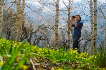 A man shoots a photo in the spring birch forest