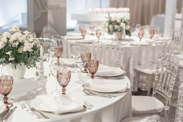 Round Banquet table served. Interior of restaurant for wedding dinner, ready for guests. Decorated with floral arrangement. Dishes, wine glasses and napkins. Catering concept.