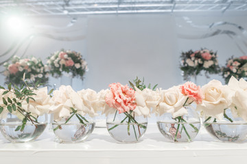 Small flower arrangements in ball glass vases. The table of the newlyweds. Interior of restaurant for wedding dinner, ready for guests. Catering concept.