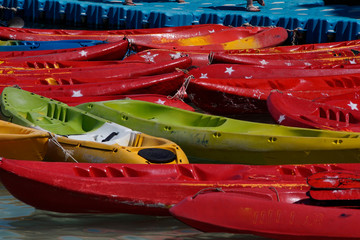 Mixed color of kayak are floating at a pier 