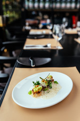 Molecular Creative Fine Dining: Hokkaido Scallop with green apple, hazelnut and shellfish veloute. Served in white plate on leather mat.