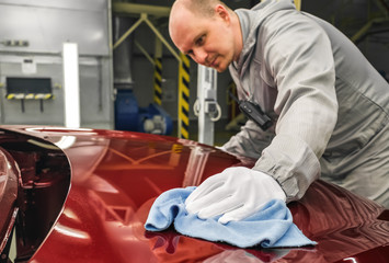 An employee of the car body painting shop checks the quality