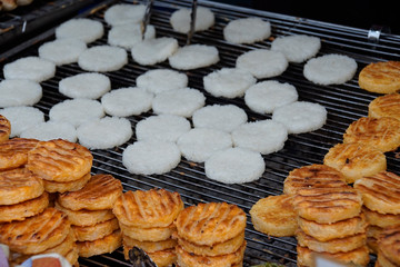 White sticky rice plate on a charcoal stove with brown backed sticky rice stack on the stove edge