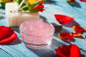 beauty products with rose flowers and petals on blue wooden table background