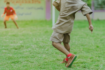 Fototapeta premium Asian boys practice kicking the ball to score goals in the public football field.
