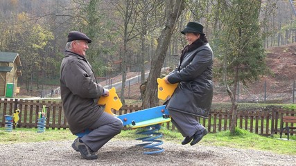 Grandparents couple having fun at child playground, smiling laughing in nature