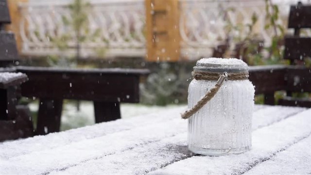 Pure white snow falling on te wooden table bench and retro glass bottle