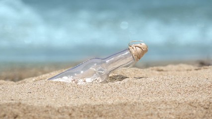 Message in a bottle on the tropical beach of exotic island, turquoise waves of the sea in background