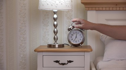 Clock and night light on bedside table, hand take the clock, vintage bedroom