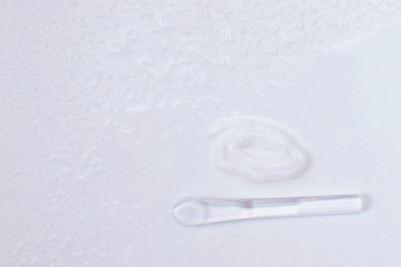 Cream, spatula for applying cream on a light background among water droplets