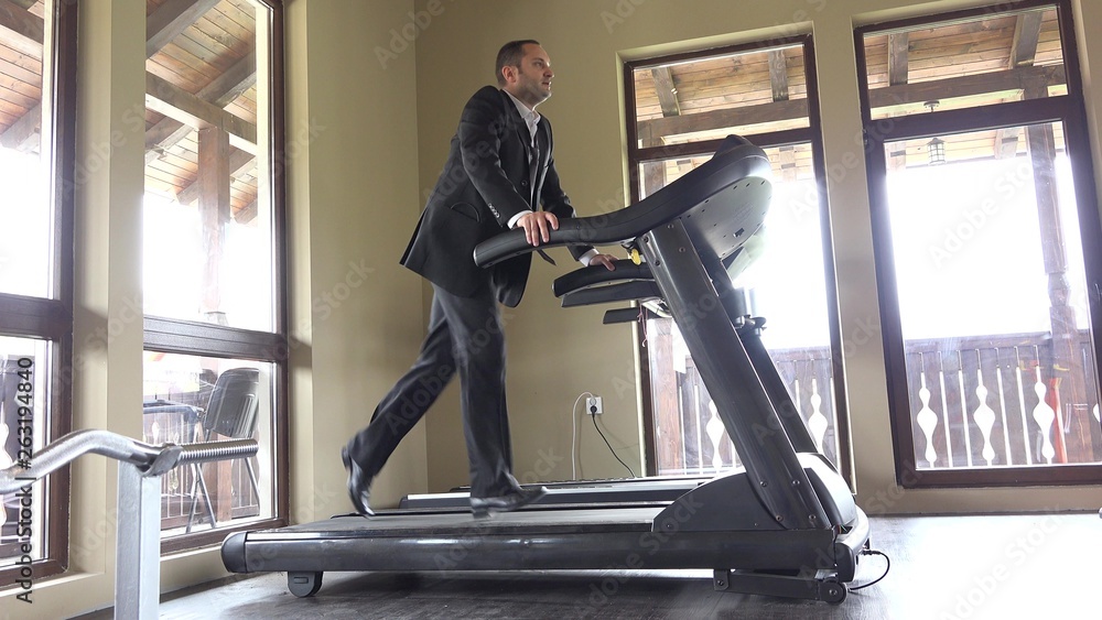 Wall mural Man with suit running on gym machine, work break, running to succes