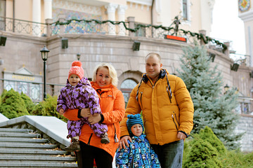 Mom and dad with two children walking outdoor, warm weather. Lifestyle portrait parents and kids in happiness at the outside, moments of life 