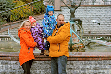 Obraz na płótnie Canvas Mom and dad with two children walking outdoor, warm weather. Lifestyle portrait parents and kids in happiness at the outside, moments of life 