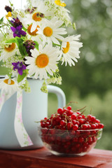 A bouquet of wildflowers and a glass bowl of red currant	
