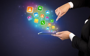 Hand holding tablet and application icons falling inwards
