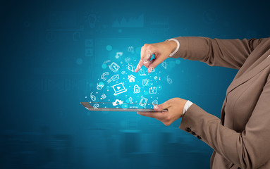Elegant hand holding tablet with chalk drawn social media symbols above
