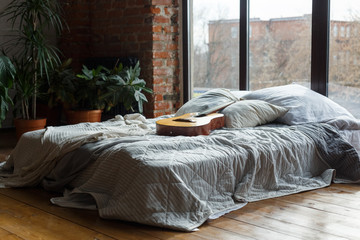 Comfortable bedroom interior with wide bed near windows, loft style. Modern interior with green...