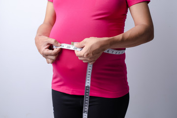 Pregnant women wear pink shirts. who measured her stomach with a tape measure on a white background