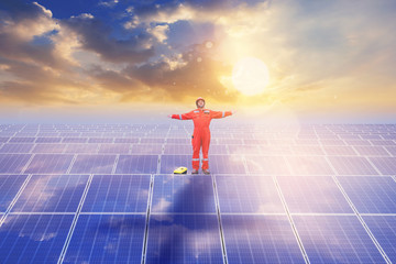 Electrical and instrument technician has relax by open arms after maintenance electric system at solar panel field with sunsut background and reflection on solar panels.