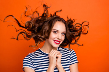 Close up photo beautiful she her lady red lipstick pomade hands arms together hair curls flight overjoyed peaceful mood wear casual striped white blue t-shirt clothes isolated orange bright background
