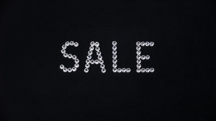 Word Sale made of shiny white swarovski crystals placed on black leather