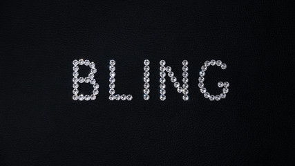 Word Bling made of shiny white swarovski crystals placed on black leather