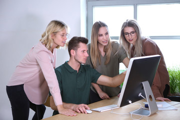 Junge Erwachsenen besprechen am Computer eine Arbeit