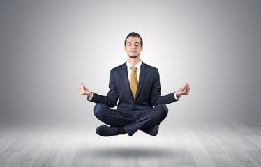 Businessman levitates and sitting in yoga position in an empty infinity space
