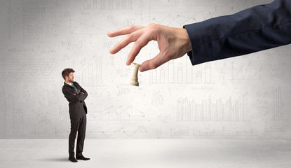 Little businessman is afraid to make the next step in his chess game with graphs, charts and...