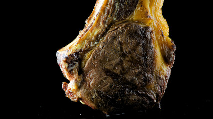 Closeup of the bottom of a t-bone steak grilled on an isolated black background
