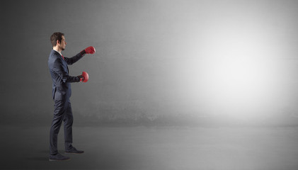 Businessman fighting with boxing gloves in an empty space
