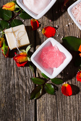 beauty product samples with rose flowers and buds on weathered old wooden table