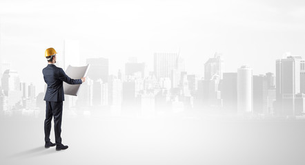 Young supervisor architect standing and looking at a big city panorama
