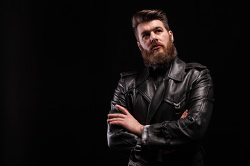 Attractive bearded man keeping his arms crossed over blac background