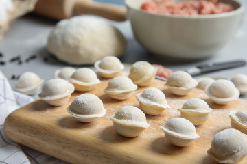 Board with raw dumplings on table, closeup. Process of cooking