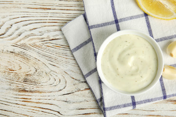 Flat lay composition with garlic sauce on wooden background. Space for text
