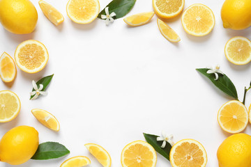 Frame made of lemons, leaves and flowers on white background, top view with space for text. Citrus...