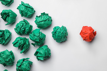 Green balls of crumpled paper following red one on white background, top view. Leadership concept