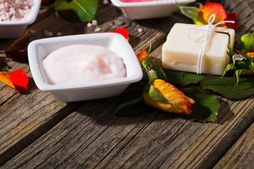 beauty product samples with rose flowers and buds on weathered old wooden table