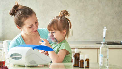 woman makes inhalation to a child at home. brings the nebulizer mask to his face. inhales the vapor...