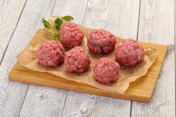 Raw meatball over wooden background