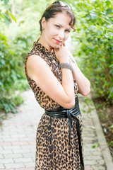 Portrait of happy and attractive young caucasian woman in nice dress in the summer park's alley. Beautiful natural green background.