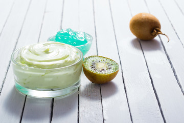 moisturizer and anti aging gel with kiwi on white wooden table