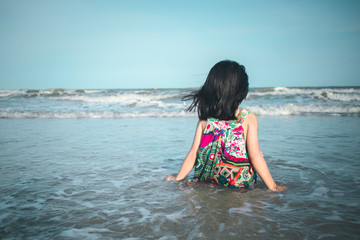 Fototapeta na wymiar little girl sitting looking at the beach