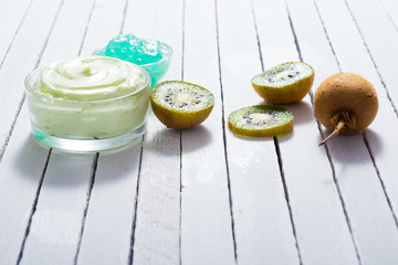 moisturizer and anti aging gel with kiwi on white wooden table