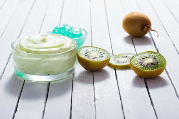 moisturizer and anti aging gel with kiwi on white wooden table