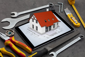Tablet with construction tools and 3d home plan concept
